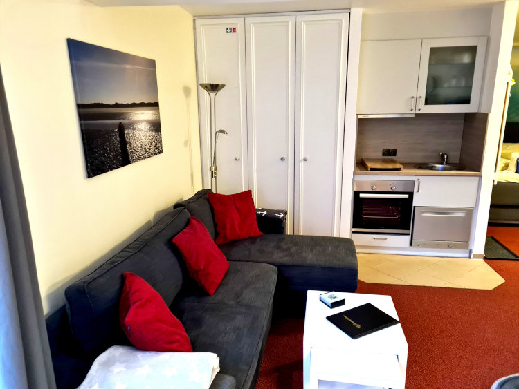 Ferienwohnung 208 für 2 Personen in der Strandburg auf Juist - gemütliches Sofa mit voll ausgestatteter Küche.